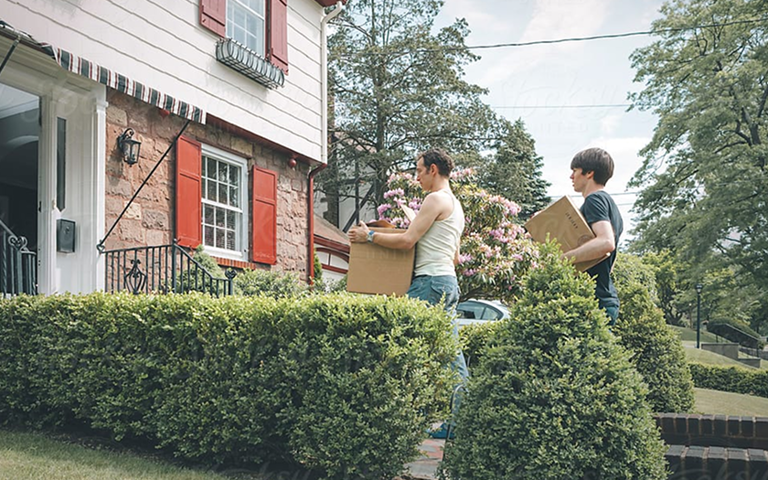 Man and a bog carrying boxes into a house
