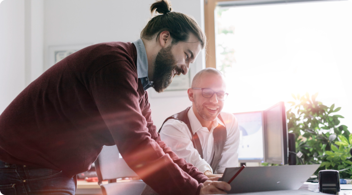 Image of two men looking at a notebook together